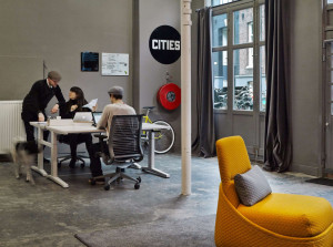 Workers inside modern office space with yellow armchair, mobile office chairs, and collaborative table